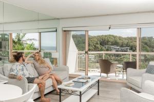 a group of three women sitting on a couch in a living room at Charlesworth Bay Beach Resort in Coffs Harbour