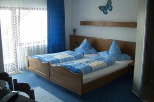 a bedroom with a bed with blue pillows at Hotel Wegis Garni in Bermatingen