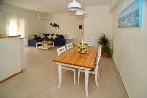 kuchnia i salon z drewnianym stołem i krzesłami w obiekcie The Bluehouse - Spacious top floor flat with parking, by Mon Repos beach w Korfu
