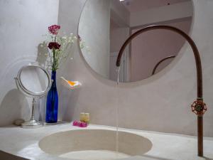a bathroom with a sink with a mirror and flowers at Hotel Pochote Mazunte in Mazunte