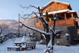 a house with a table and benches in the snow at Chalet Parea in Metamorfosi