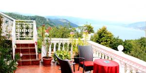 a balcony with a table and chairs and a view of the water at Gajanovic Rooms in Donji Milanovac