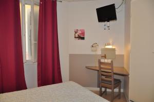 1 dormitorio con mesa y cortina roja en Hotel Lux en Grenoble
