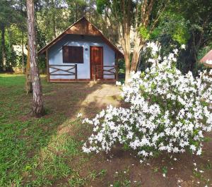 a small cabin with white flowers in front of it at Rancho Pôr Do Sol in Arapeí