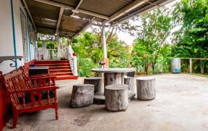 eine Terrasse mit einem Tisch, Stühlen und Bäumen in der Unterkunft Casa Campesina Hostel in Armenia