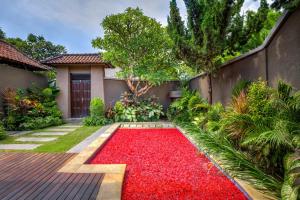 a garden with a red carpet in front of a house at Gracia Bali Villas & Apartment in Seminyak