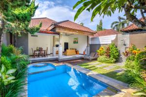 un patio trasero con piscina y una casa en Gracia Bali Villas & Apartment, en Seminyak