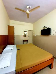 Un dormitorio con una cama con ventilador de techo. en Veekay Residency, en Bangalore