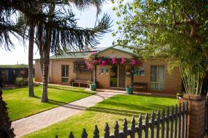 ein Haus mit einem Zaun vor einem Hof in der Unterkunft Capricorn Holiday Park in Carnarvon