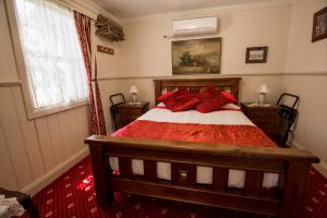 a bedroom with a bed with red pillows and a window at Mill house in Walhalla