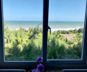 a view of the ocean from a window with purple flowers at Oceanward Hotel & Resort in Long Hai