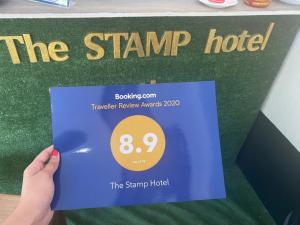 een persoon die een bord omhoog houdt dat het postzegelhotel leest bij The Stamp Hotel in Ko Tao