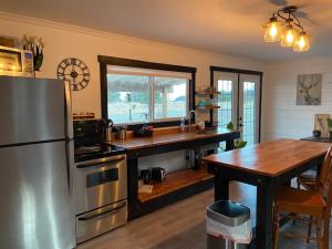 a kitchen with a stainless steel refrigerator and a wooden table at Sunrise Cabin secluded beach front accommodation in Sandspit
