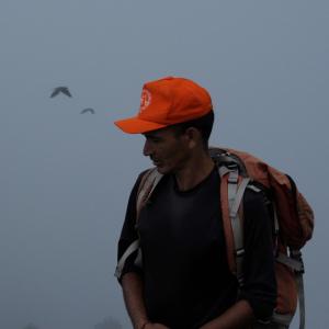 un homme portant un chapeau orange avec un sac à dos et un cerf-volant dans l'établissement Solitude Homestay, Agoda, à Uttarkāshi