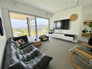a living room with a leather couch and a television at Spectacular Bilgola Beachhouse in Avalon