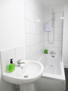 a white bathroom with a sink and a tub at Emmanuel Church Apartments in Warrington