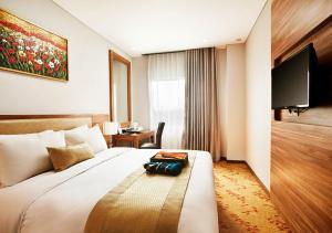um quarto de hotel com uma cama grande e uma televisão em Grand Serela Yogyakarta by KAGUM Hotels em Yogyakarta