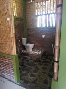 a bathroom with a toilet in a brick wall at Bale'ku in Pangandaran