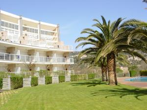 a building with a palm tree in front of a yard at Apartamentos Rodamar in L'Estartit