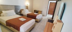 a hotel room with two beds and a bathroom at Tiara Inn in Ternate