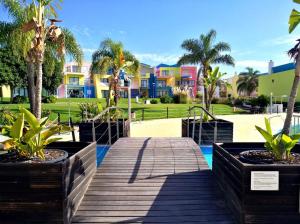 a wooden boardwalk with palm trees and houses in the background at Marina de Albufeira Orada Resort - 2-bed apartment with huge pool in Albufeira