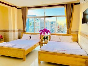 two beds in a room with a window at Mekong Rose Hotel in Can Tho
