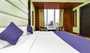 a bedroom with a large white bed with purple pillows at hotel black diamond Zirakpur bus stand in Zirakpur