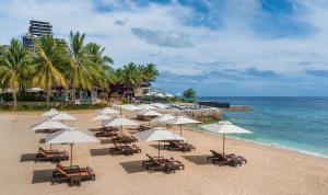 einen Strand mit Liegestühlen und Sonnenschirmen und dem Meer in der Unterkunft Crimson Resort and Spa - Mactan Island, Cebu in Mactan