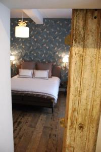 a bedroom with a bed and a wall covered in wallpaper at Monsieur Doute in Durbuy