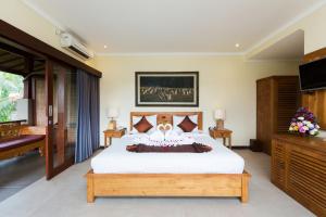 a bedroom with a large bed and a television at Alamdini Resort Ubud in Ubud