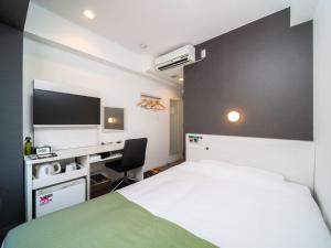 a bedroom with a bed and a desk with a tv at Super Hotel Shinagawa Shinbanba in Tokyo