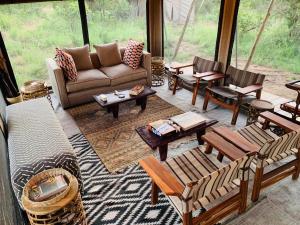 sala de estar con sofá, mesas y sillas en Simbavati Trails Camp, en Reserva Timbavati