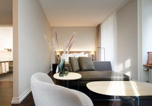 a living room with a couch and a table and chairs at Sorell Hotel Zürichberg in Zurich