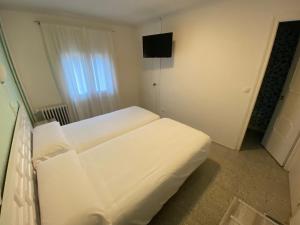 a white bed in a room with a television at HOTEL GRIU in Encamp