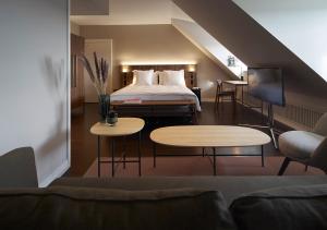 a hotel room with a bed and a couch and tables at Sorell Hotel Zürichberg in Zurich