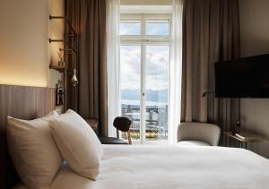 a white dog sitting on top of a bed in front of a window at Sorell Hotel Zürichberg in Zurich