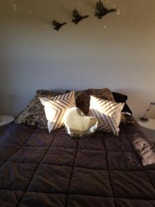 Una cama con almohadas y un osito de peluche. en Waihakeke Cottage, en Carterton