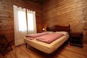 1 dormitorio con 1 cama con pared de madera en Residence Hotel Montegargnano, en Gargnano