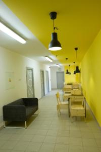 a room with tables and a couch and yellow walls at Hostel U Zlatého kohouta in Kroměříž