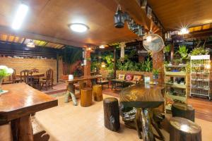 un restaurante con mesas de madera, sillas y plantas en Baan Maihorm Guesthouse en Mae Chan
