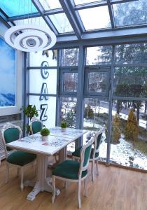 jadalnia ze stołem, krzesłami i oknami w obiekcie Park Luxury Rooms w mieście Predeal