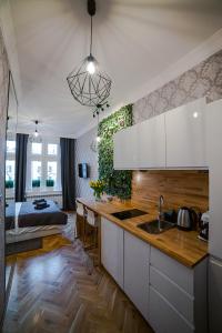 una cocina con armarios blancos y una cama en una habitación en Słowackiego Apartments, en Cracovia