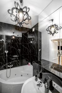 a bathroom with a sink and a bath tub and a chandelier at Słowackiego Apartments in Krakow