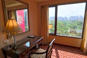 Habitación de hotel con escritorio y ventana grande. en Rido Hotel en Taipéi