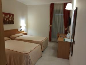 a hotel room with two beds and a television at El Eden in El Ejido