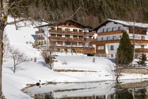 um edifício na neve ao lado de um corpo de água em Landhaus Panorama em Berwang