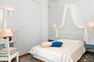 a white bedroom with a bed and a window at Atlantis Beach Villa in Perivolos