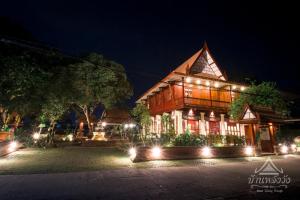 un bâtiment avec des lumières devant lui la nuit dans l'établissement Baan Lhang Wangh บ้านหลังวัง, à Phitsanulok