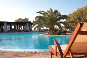 a swimming pool with a chair and a palm tree at Atlantis Beach Villa in Perivolos