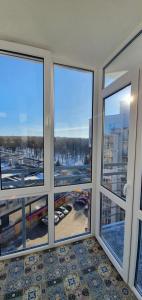 um quarto com quatro janelas com vista para um parque de estacionamento em Затишна квартира з виглядом на парк em Ternopilʼ